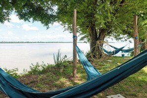 A hammock set up between trees by a lake. - Souchitra Riverside Guesthouse (Champasack District)