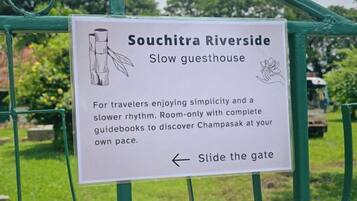 Señal para Souchitra Riverside, un alojamiento tranquilo, con una reja y un sendero.