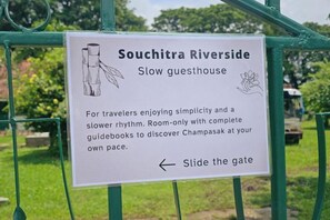 A sign for Souchitra Riverside, a slow guesthouse, with a gate and a pathway. - Souchitra Riverside Guesthouse (Champasack District)