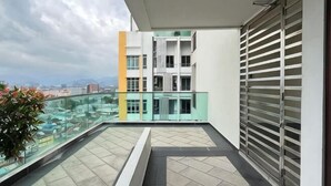 Een balkon met glazen hekwerk, een uitzicht op een stadsbeeld en een gebouw met een modern ontwerp.