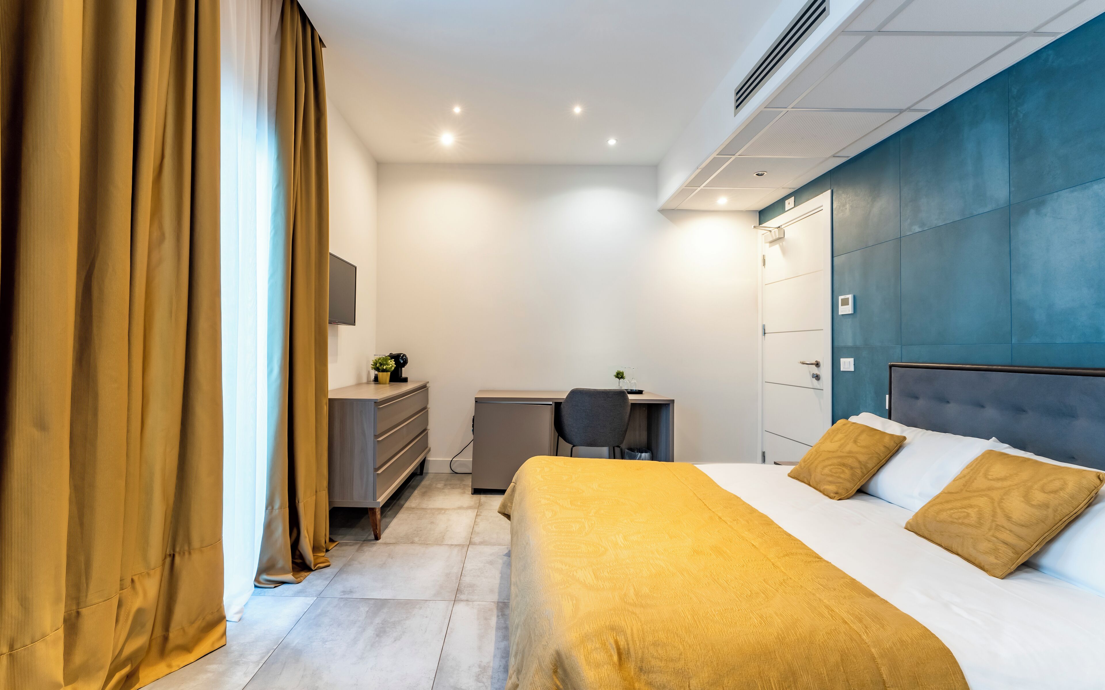 Een moderne hotelkamer met een bed, bureau en garderobe.