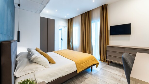 Una habitació d'hotel moderna amb un llit gran, televisió de pantalla plana, escriptori i un armari.