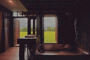 Une salle de bain rustique avec un banc en bois, un lavabo et un espace douche.