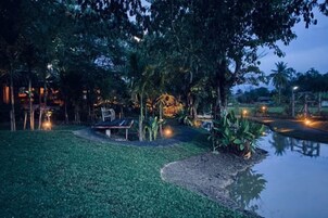 A nighttime outdoor area with a bench, a small pond, and trees.
