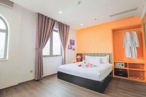 Una camera d'albergo con un letto, una finestra con tende, un armadio e un comodino.