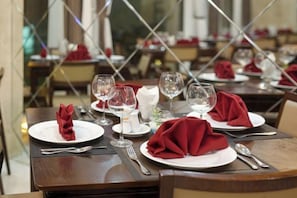 A restaurant setting with tables set for dining, featuring white plates, red napkins, and wine glasses.