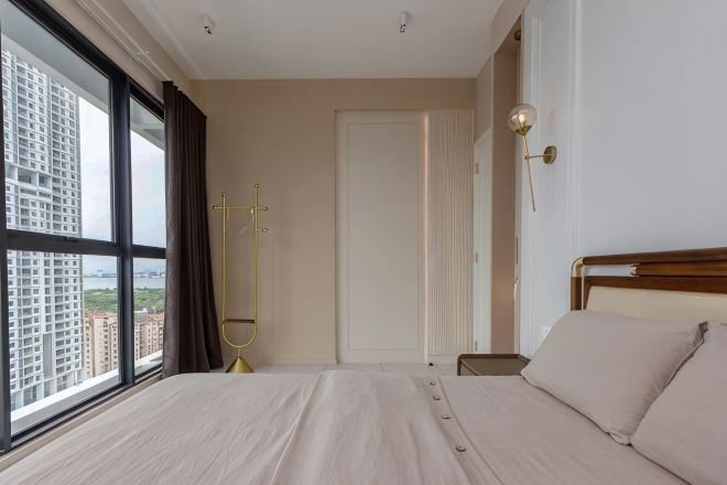 A bedroom with a large window, a bed, a bedside table, and a door.