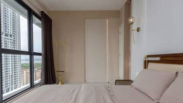A bedroom with a large window, a bed, a bedside table, and a door.