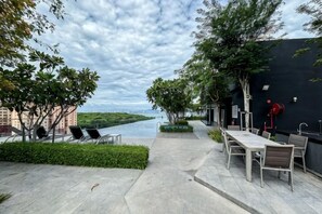 An outdoor terrace with tables and chairs, a river view, and a black wall with a red fire hydrant. - Designer Suites George Town + LG Water Purifier【City View】 (Jelutong)