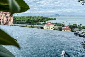 A view of a waterfront hotel with a pool, a building with a red roof, and a body of water in the background. - Designer Suites George Town + LG Water Purifier【City View】 (Jelutong)
