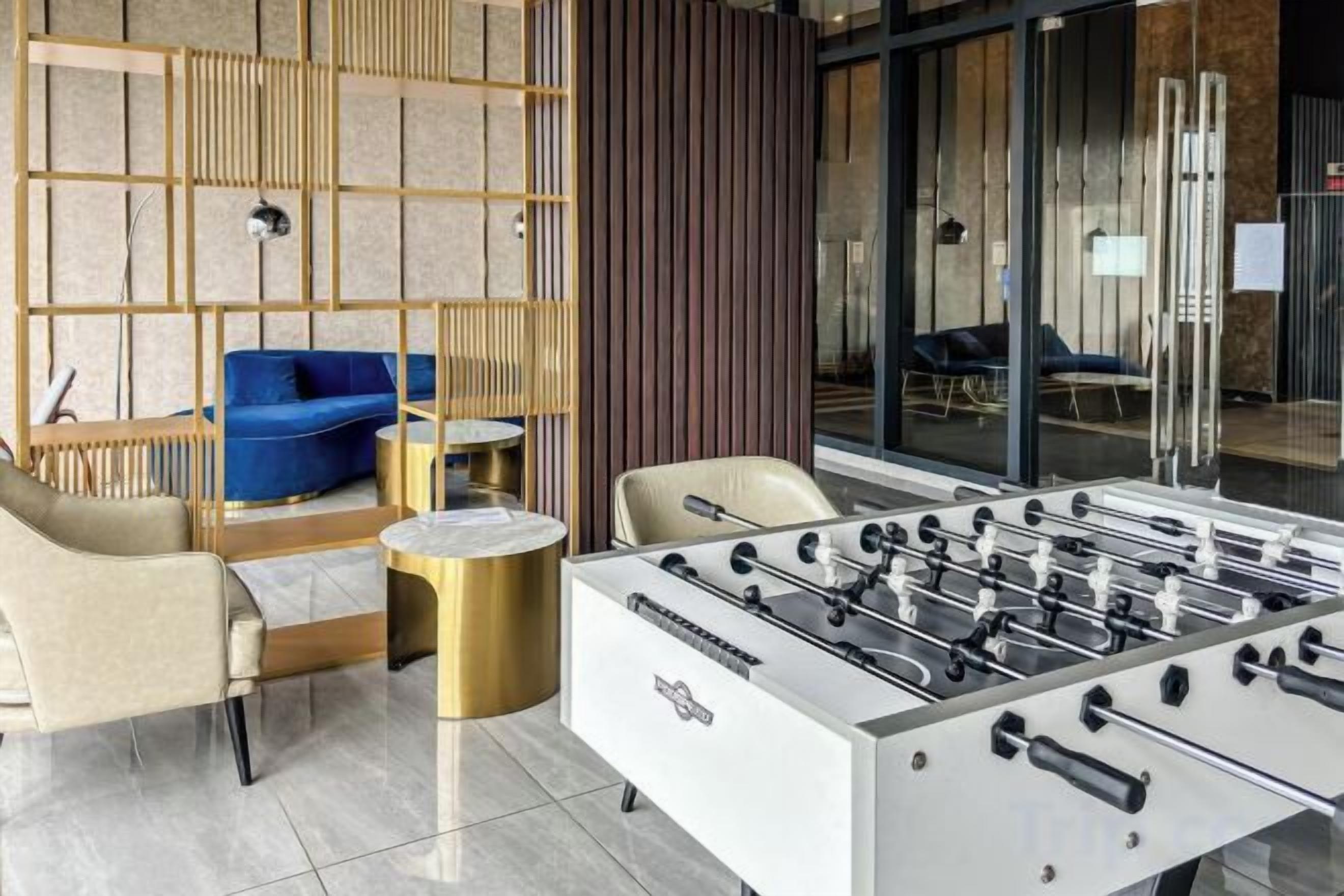 A modern indoor space with a foosball table, a blue sofa, and a seating area with a coffee table.