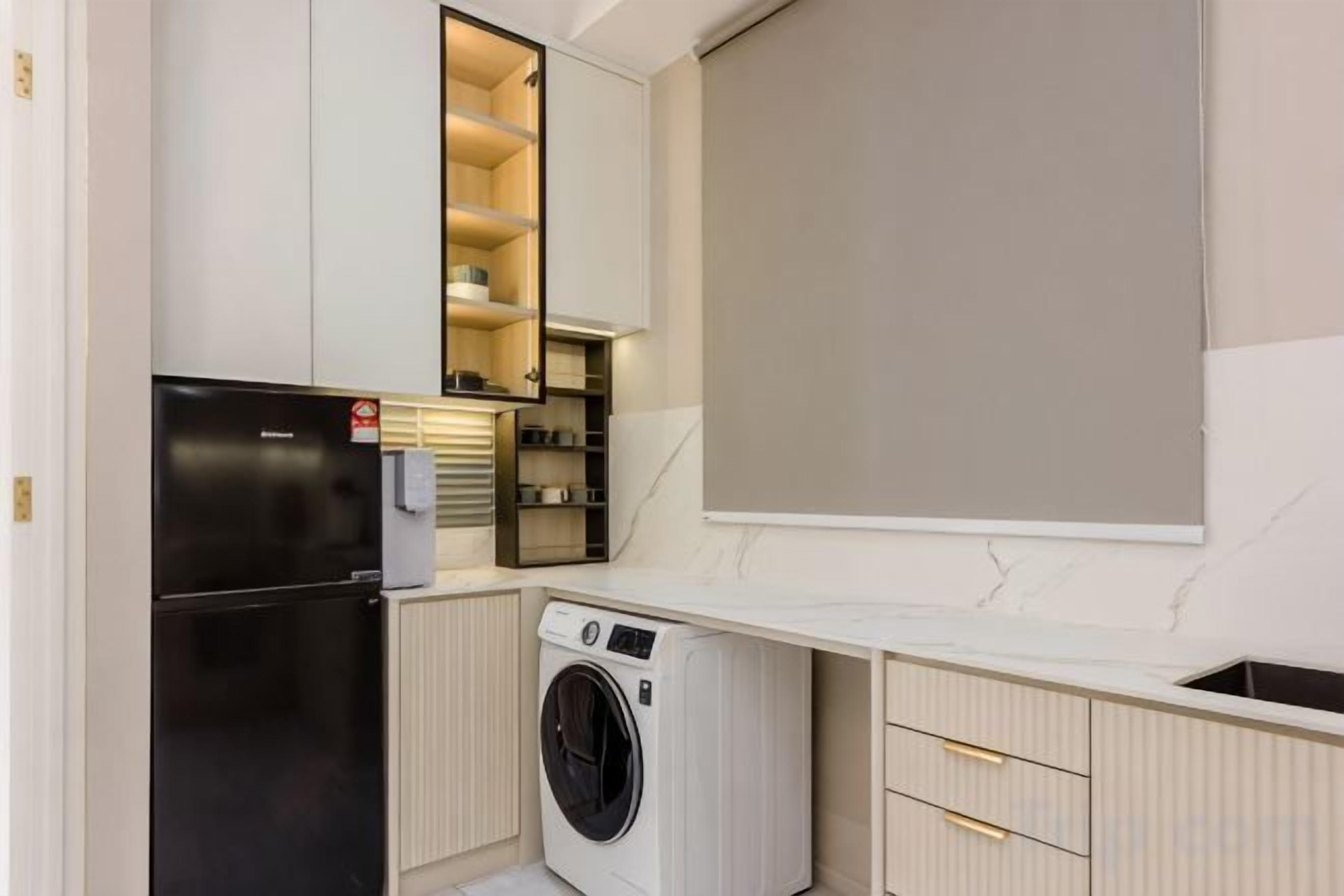 Una cocina compacta con lavadora integrada, refrigerador y microondas.