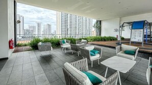 Eine Dachterrasse mit Sitzgelegenheiten im Freien, einem Feuerlöscher und Blick auf die Stadtlandschaft.