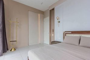 A hotel room with a bed, a door, a coat rack, and a wall-mounted light fixture. - Designer Suites George Town + LG Water Purifier【City View】 (Jelutong)