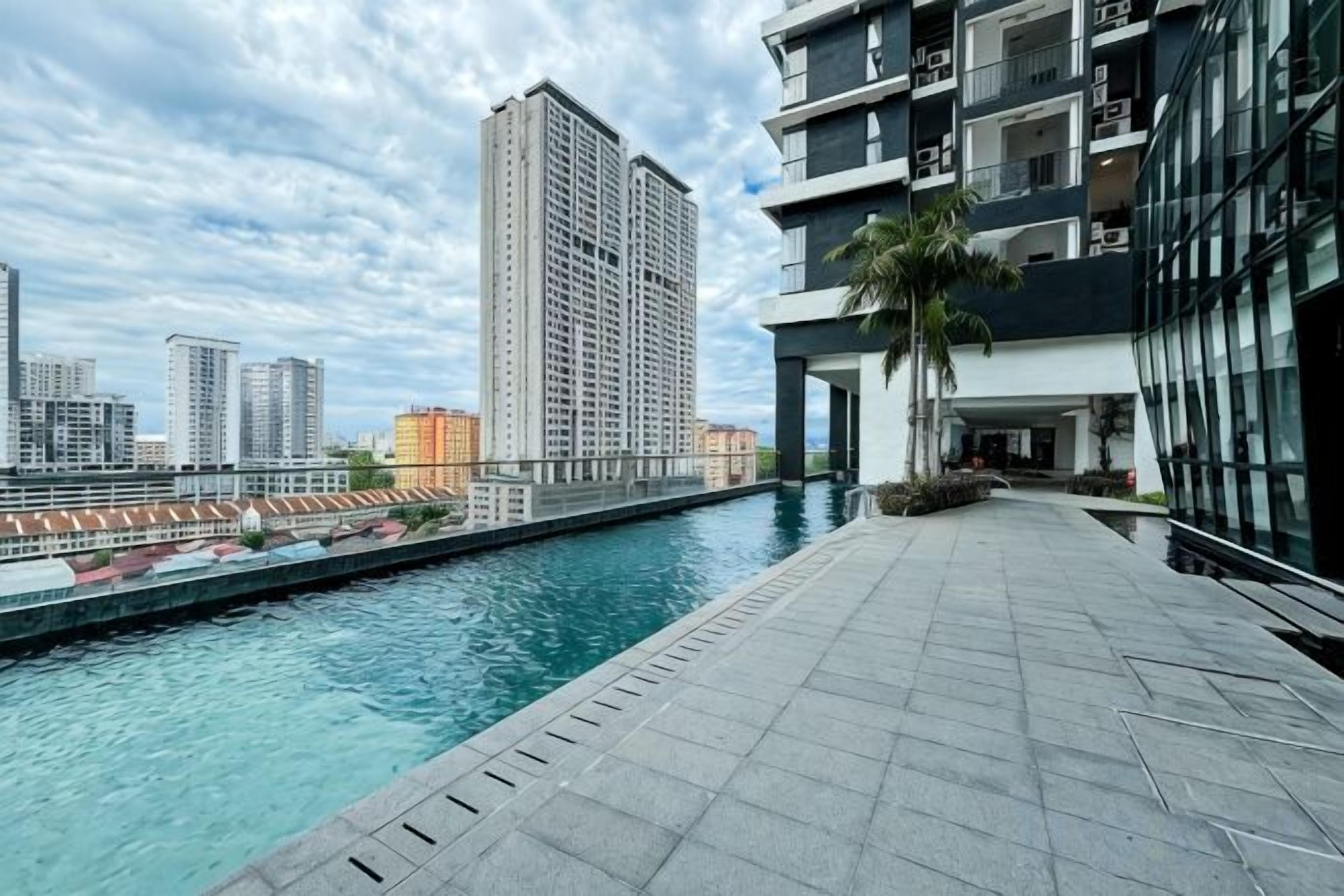 A swimming pool area with a cityscape view, modern buildings, and a paved walkway.