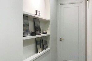 A hallway with white walls, a closed door, and shelves with framed pictures and a small decorative item. - Designer Suites George Town + LG Water Purifier【City View】 (Jelutong)