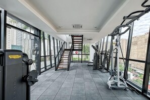 A gym with exercise equipment, a staircase, and large windows offering a city view. - Designer Suites George Town + LG Water Purifier【City View】 (Jelutong)