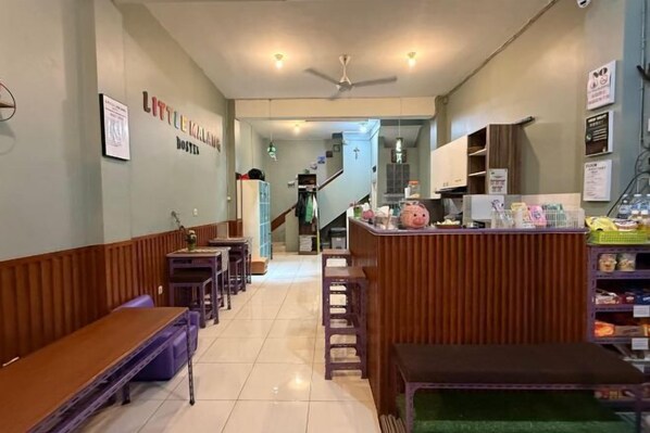 Un restaurante con bancos de madera, una barra con productos alimenticios y una escalera que sube a un nivel superior.