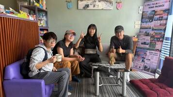 A group of people sitting on a couch and chairs in a room with a bulletin board and a small table.