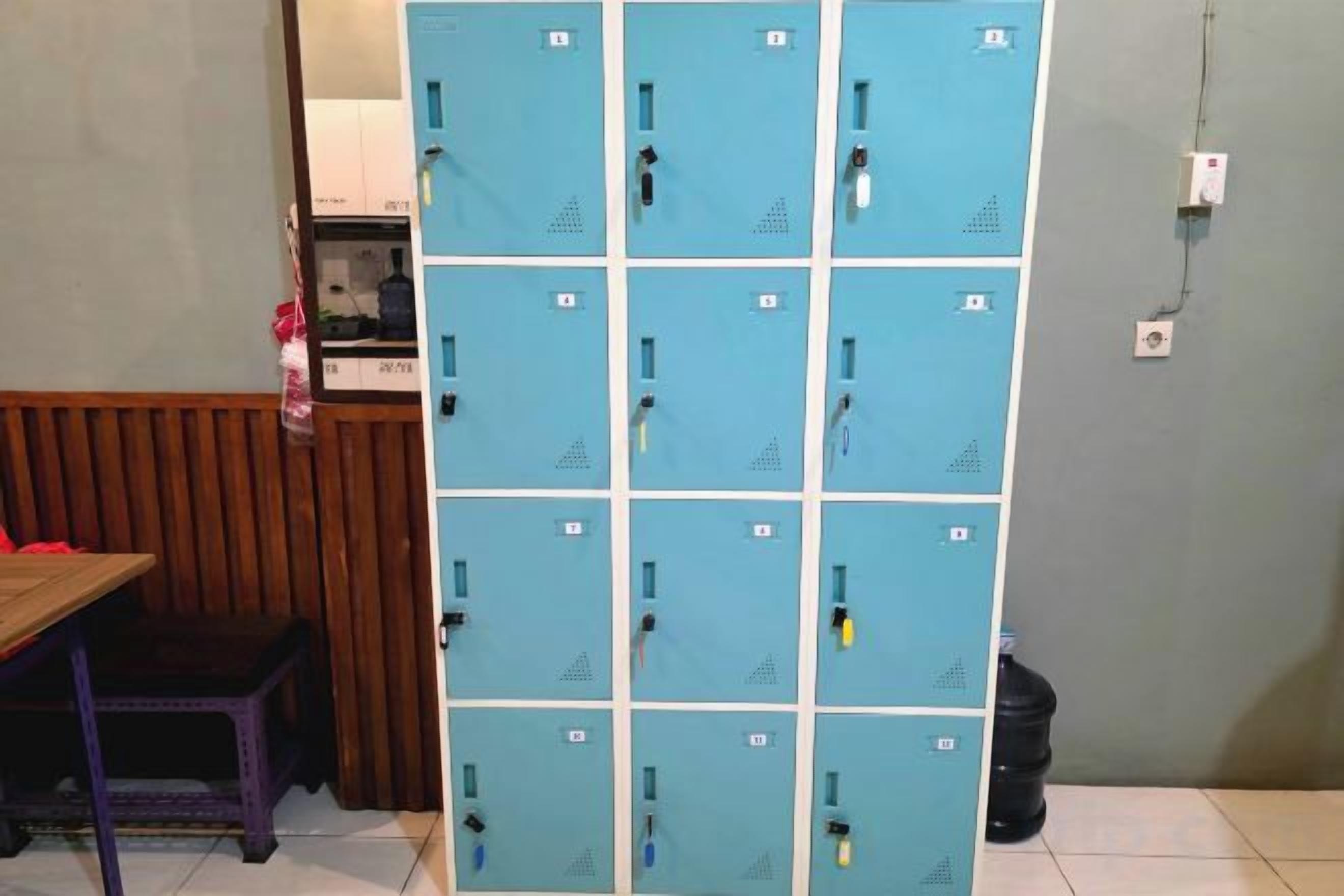 A row of blue lockers with a wooden bench and a trash bin in the foreground.