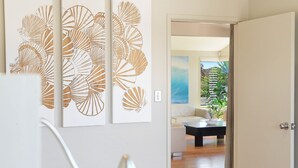A modern interior with a minimalist design, featuring a living area with a sofa and a coffee table, and a wall with a large, abstract art piece. - The Break – space, comfort and seaside fun (Culburra Beach)