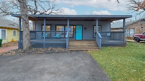 A two-story building with a porch, a blue door, and a small staircase leading to the entrance. - Walk to AT&T Stadium! | Dream City Retreat | 3BR/2BA w/Firepit & Modern Comforts (Arlington)