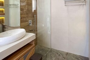A bathroom with a white sink, a glass shower enclosure, and a marble floor. - Landmark Villas (Bali)