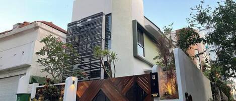 Un edificio moderno con un diseño arquitectónico único, que presenta una fachada curva y una entrada destacada con una puerta de madera.