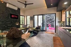 A modern living room with a flat-screen TV, a sofa, a glass coffee table, and a large window. - Landmark Villas (Bali)