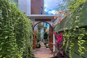 A pathway leading to a building entrance, surrounded by greenery and an archway. - Landmark Villas (Bali)