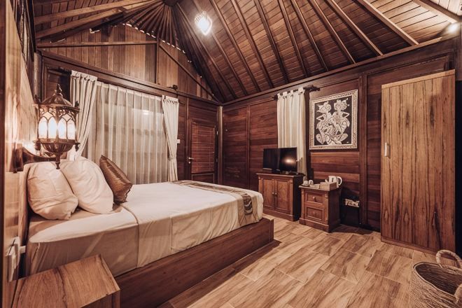 Una habitación con piso de madera, una cama, un televisor y un cuadro en la pared.