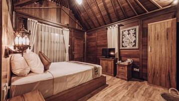 Una habitación con piso de madera, una cama, un televisor y un cuadro en la pared.