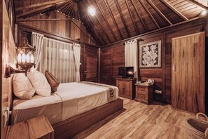 Quarto de madeira com uma cama, uma televisão e um quadro na parede.