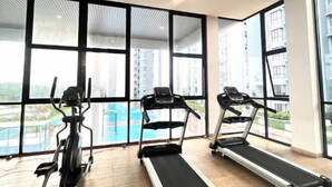A gym with three treadmills and an elliptical machine, large windows, and a view of a swimming pool. - IOI City, Serdang,UPM, Balakong,The Mines,Greenpark 3A (Kajang)