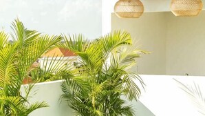 A modern outdoor area with a white wall, a wooden ceiling, and a hanging light fixture. - Coco & Pineapple Pants Hostel (Bali)