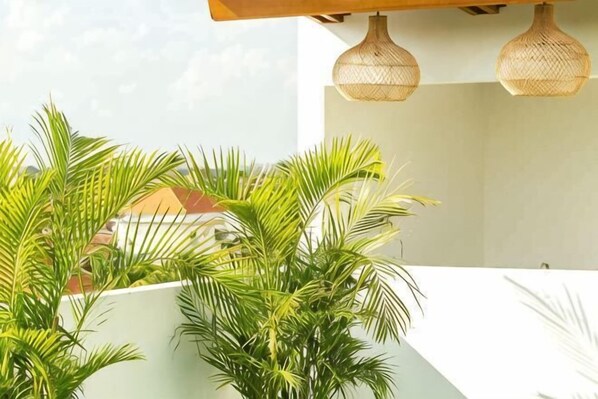 A modern outdoor area with a white wall, a wooden ceiling, and a hanging light fixture. - Coco & Pineapple Pants Hostel (Bali)