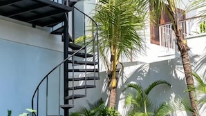 A spiral staircase leading to a balcony with palm trees. - Coco & Pineapple Pants Hostel (Bali)