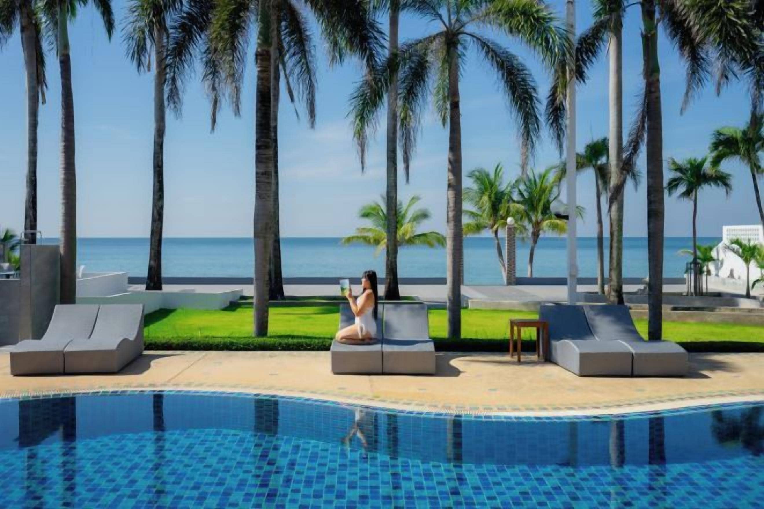 A poolside area with lounge chairs and a view of the ocean.