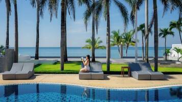 Un espace aménagé au bord de la piscine, avec des chaises longues et une vue sur l’océan.
