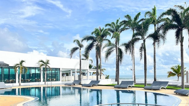 A pool area with lounge chairs, palm trees, and a view of the ocean. - Chaolao Sea Breeze Resort (Tha Mai)
