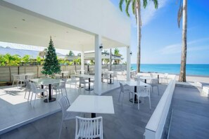 Un espace extérieur aménagé avec des tables et des chaises, un sapin de Noël et une vue sur la plage.