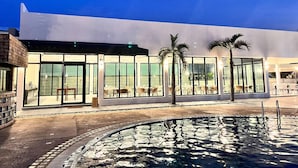 A modern building with large glass windows, outdoor seating, and a pool area. - Chaolao Sea Breeze Resort (Tha Mai)