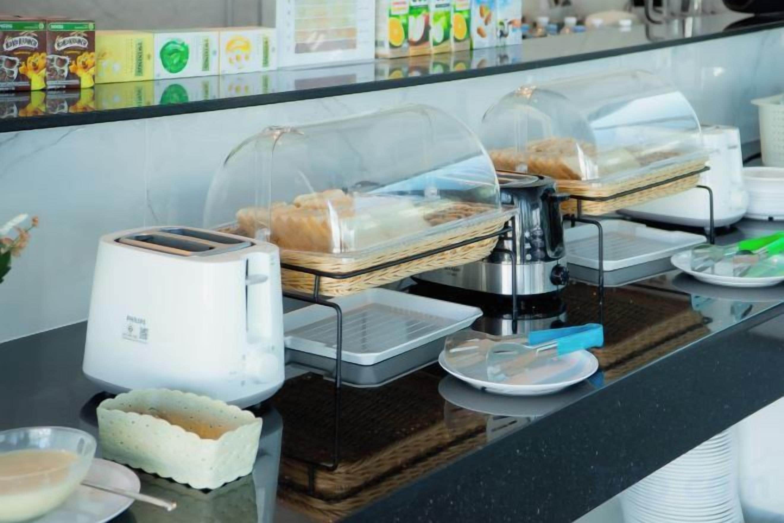 Um buffet de café da manhã com diversas opções de comida, uma máquina de café e uma torradeira.