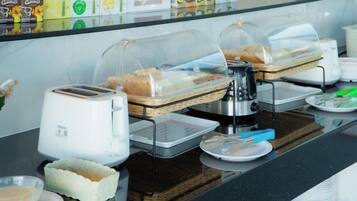 Um buffet de café da manhã com diversas opções de comida, uma máquina de café e uma torradeira.