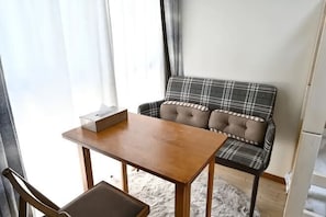 A room with a plaid sofa, a wooden table, and a chair. - Rose Park Second House (Funabashi)