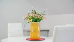 A white table with a yellow vase containing colorful flowers. - Utility Street - 1-bed Apt + Parking (Belfast)