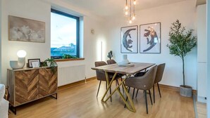 Uma sala de jantar moderna com uma mesa e cadeiras de madeira, um aparador decorativo e obras de arte nas paredes.