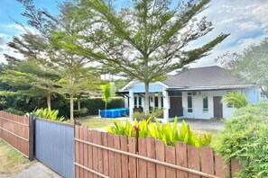 Een woonhuis met een omheinde tuin, een zwembad en een huis met pannendak.