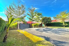 A residential driveway with a gated entrance, a palm tree, and a red umbrella. - Tepak Nusuk Private Pool Homestay 5 Bedrooms 4 Bathrooms (Kota Bharu)