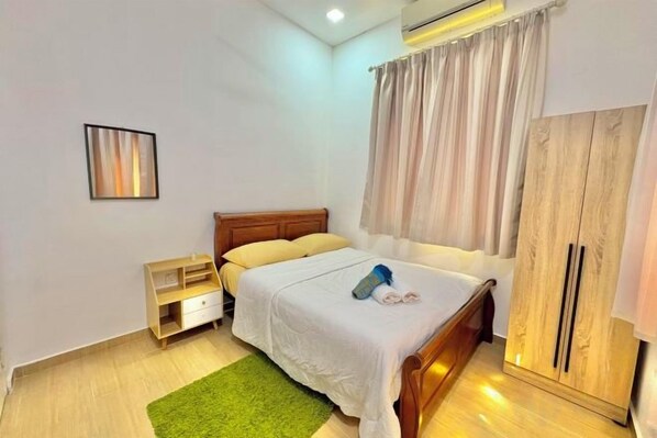 A bedroom with a bed, a nightstand, a wardrobe, and a green rug. - Tepak Nusuk Private Pool Homestay 5 Bedrooms 4 Bathrooms (Kota Bharu)